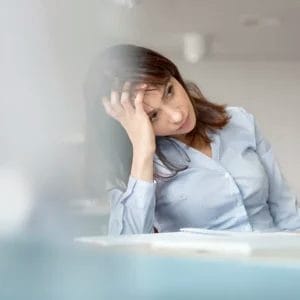 A thoughtful professional woman in an office setting, enhancing productivity with Elevate Your Organization's Culture and Performance With CEEK.