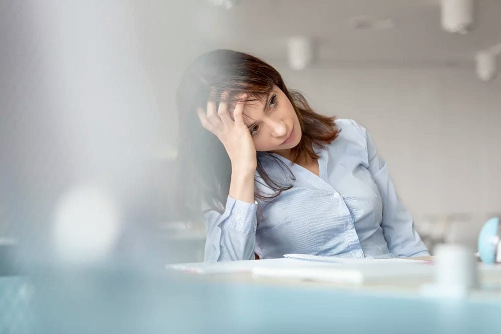 A thoughtful professional woman in an office setting, enhancing productivity with Elevate Your Organization's Culture and Performance With CEEK.