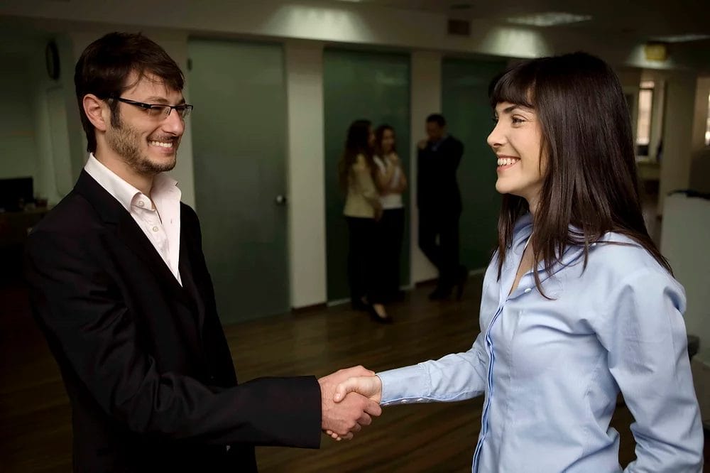 Business professionals shaking hands in an office setting, enhancing culture and performance, only available at Elevate Your Organization's Culture and Performance With CEEK.