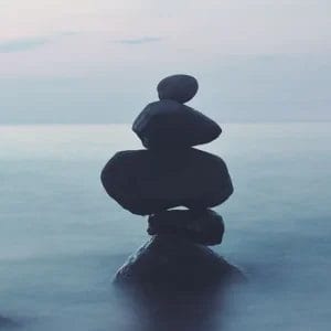 Stacked stones on a serene lakeshore at twilight, symbolizing balance and harmony, only available at Elevate Your Organization's Culture and Performance With CEEK.