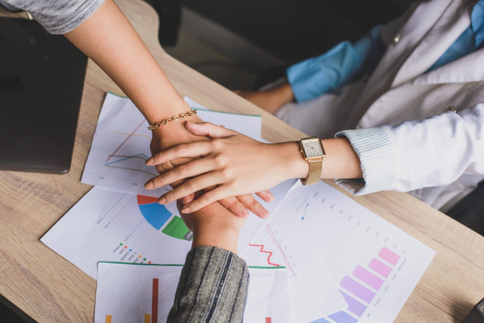 Collaborative teamwork over business charts, enhancing culture and performance, exclusively at Elevate Your Organization's Culture and Performance With CEEK.