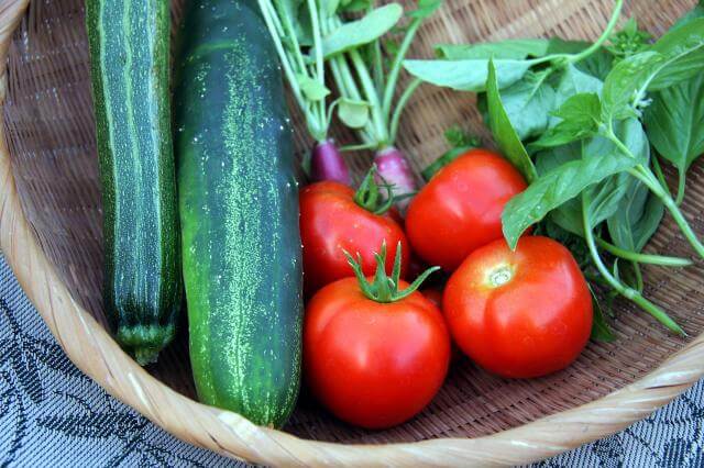 Fresh tomatoes, cucumbers, and greens in a wicker basket, showcasing vibrant produce, only available at Elevate Your Organization's Culture and Performance With CEEK.