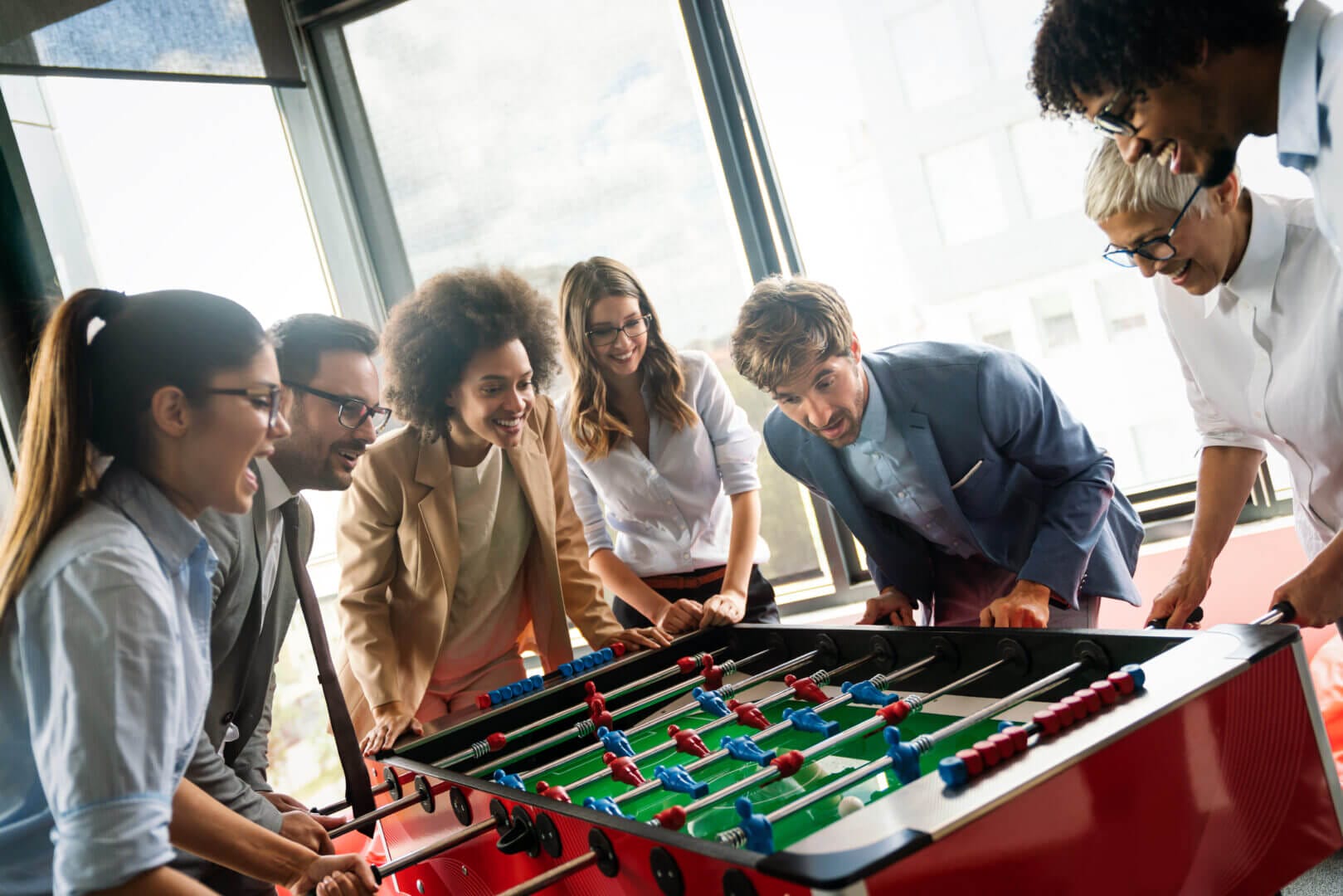 Colleagues enjoy table football in a vibrant office, fostering team spirit at Elevate Your Organization's Culture and Performance With CEEK.