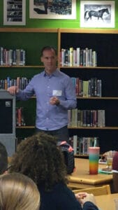 Speaker engaging audience in a library setting, enhancing teamwork skills, only available at Elevate Your Organization's Culture and Performance With CEEK.