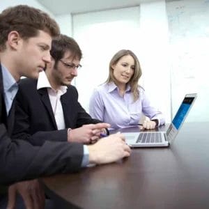 Team collaboration around a laptop in an office setting, showcasing Elevate Your Organization's Culture and Performance With CEEK expertise.