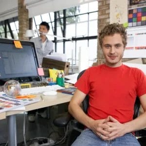 Creative workspace with a designer in a red shirt, emphasizing teamwork and innovation, only available at Elevate Your Organization's Culture and Performance With CEEK.