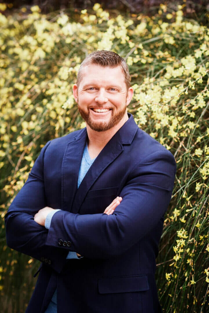 Confident man in a blue blazer smiling in nature, only available at Elevate Your Organization's Culture and Performance With CEEK.