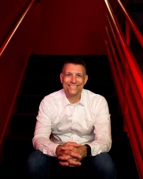 Smiling person sitting on stairs, showcasing leadership and confidence, only available at Elevate Your Organization's Culture and Performance With CEEK.