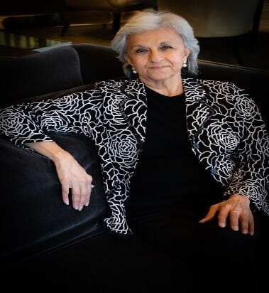 Confident woman in floral jacket seated on a sofa, embodying leadership and culture values, featured at Elevate Your Organization's Culture and Performance With CEEK.