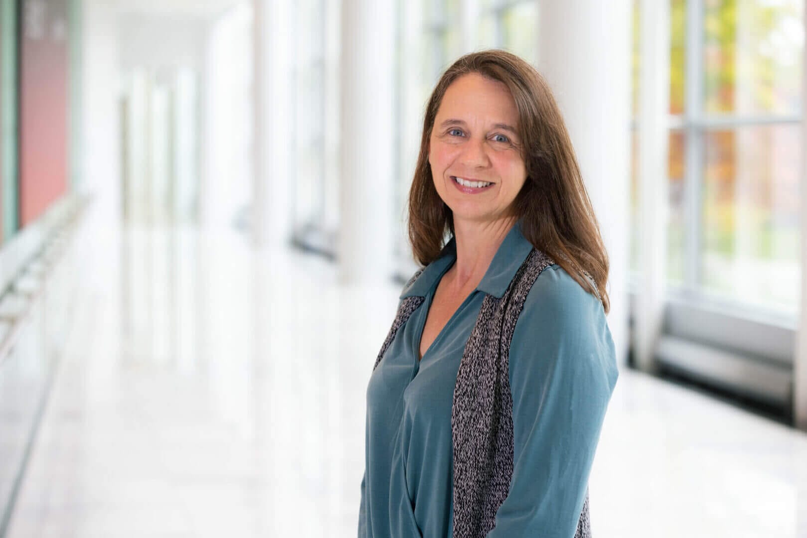 Smiling professional woman in modern office setting, enhancing company culture with Elevate Your Organization's Culture and Performance With CEEK.