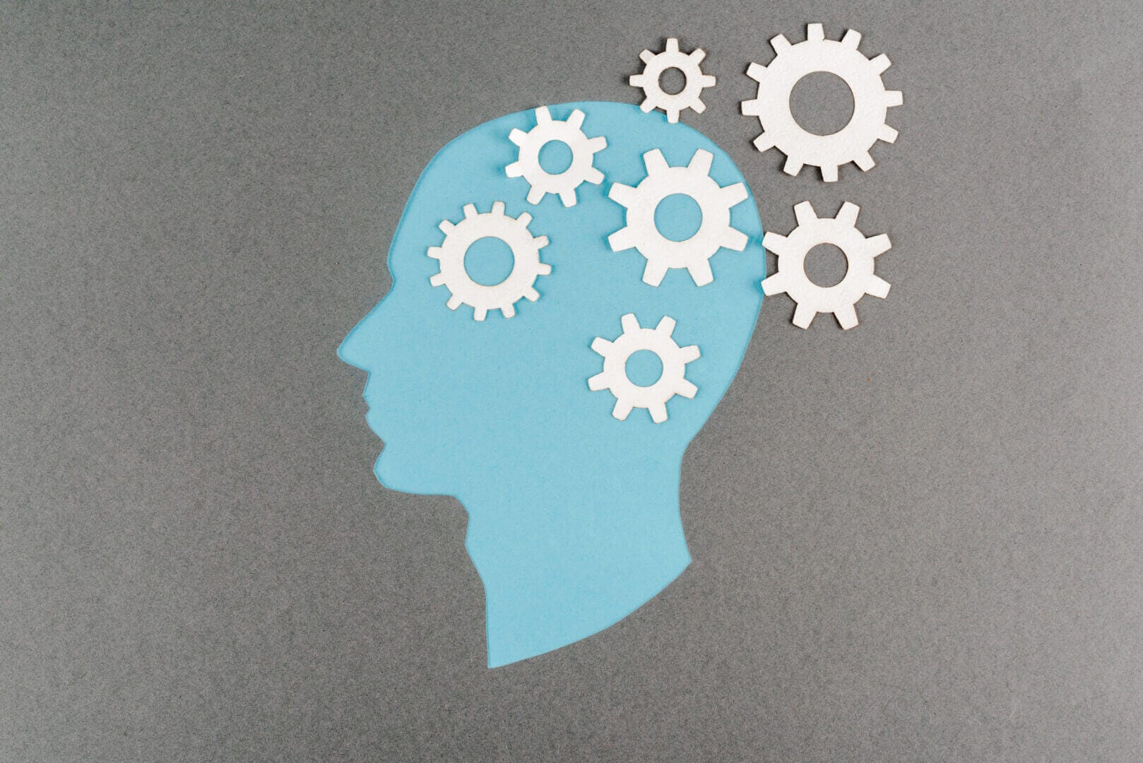 Top view of a blue human head with white gears on grey, symbolizing innovation, only at Elevate Your Organization's Culture and Performance With CEEK.