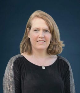 Person smiling against a blue background, featured in Elevate Your Organization's Culture and Performance With CEEK for professional development.